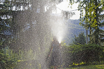 Image showing A young woman Watering a lawn in the yard of the house, a backgr