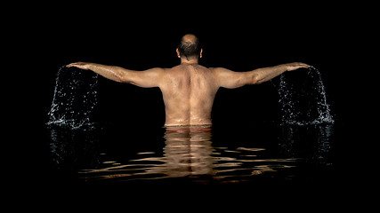 Image showing A man standing inside the water and spreads his arms