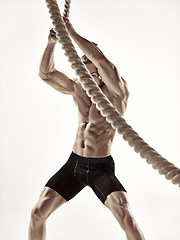 Image showing Attractive muscular man working out with heavy ropes.