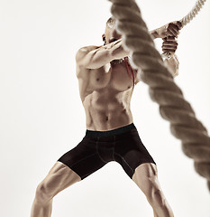 Image showing Attractive muscular man working out with heavy ropes.