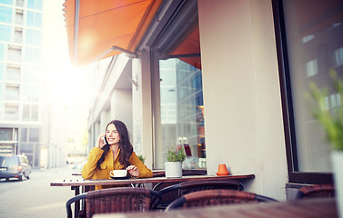 Image showing happy woman calling on smartphone at city cafe