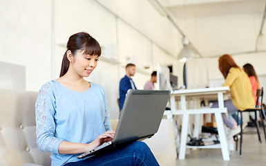 Image showing happy asian woman with laptop working at office