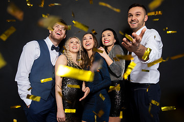 Image showing happy friends at party under confetti over black