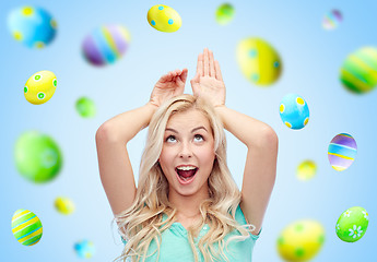 Image showing happy woman making bunny ears over easter eggs