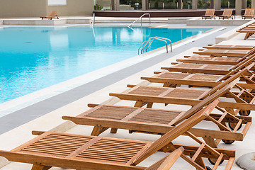 Image showing Luxury swimming pool with wooden deck chairs.