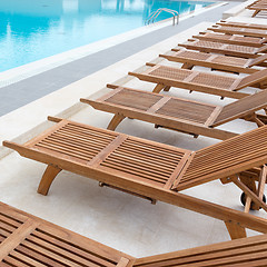 Image showing Luxury swimming pool with wooden deck chairs.