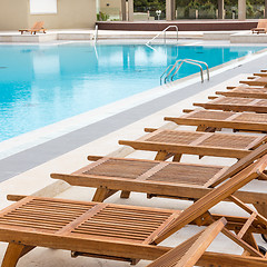 Image showing Luxury swimming pool with wooden deck chairs.