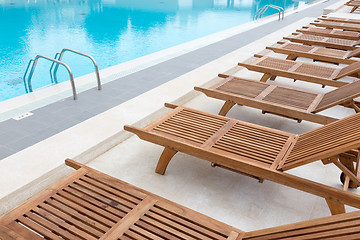 Image showing Luxury swimming pool with wooden deck chairs.