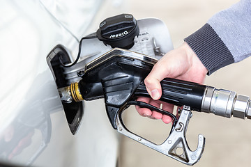 Image showing Closeup of mans hand pumping gasoline fuel in car at gas station.