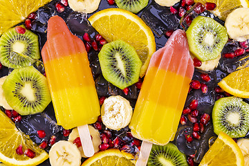 Image showing Fruit ice cream on stick with slices fruits on black