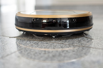 Image showing Robotic vacuum cleaner on bright marble floor