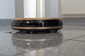 Image showing Robotic vacuum cleaner on bright marble floor