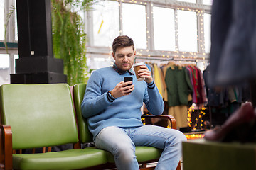 Image showing man with smartphone and coffee at clothing store