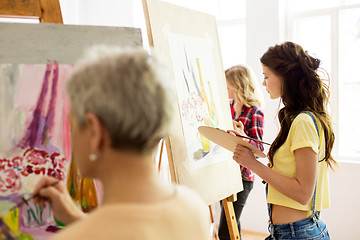 Image showing woman with easel painting at art school studio