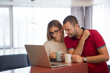 Image showing couple drinking coffee and using laptop at home