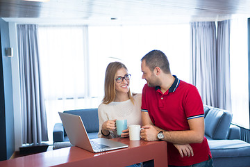 Image showing couple drinking coffee and using laptop at home