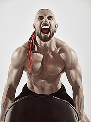 Image showing Fitness man with perfect body doing exercises with iron barrel