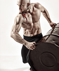 Image showing Fitness man with perfect body doing exercises with iron barrel