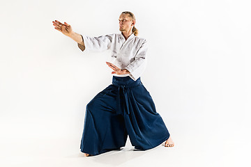 Image showing Aikido master practices defense posture. Healthy lifestyle and sports concept. Man with beard in white kimono on white background.