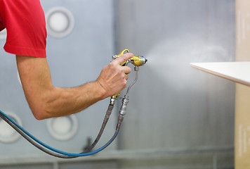 Image showing worker hand sprays urethane finish to board