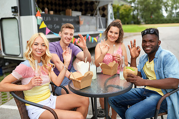 Image showing happy friends with drinks eating at food truck