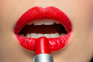 Image showing close up of woman applying red lipstick to lips