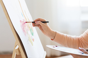 Image showing artist with palette and brush painting at studio