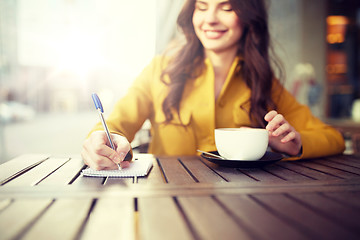 Image showing happy woman with notebook and cappucino at cafe