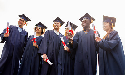 Image showing happy students in mortar boards with diplomas