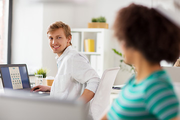 Image showing happy creative workers with laptops at office