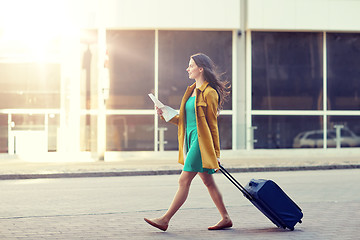 Image showing happy young woman with travel bag and map in city