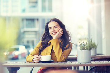 Image showing happy woman drinking cocoa at city street cafe