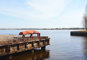 Image showing Upturned red boat on a jetty above the sea