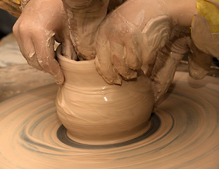 Image showing Beginner and teacher in process of making clay bowl on pottery w