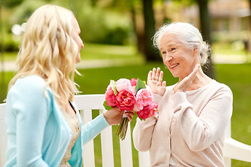 Image showing daughter giving flowers to senior mother at park