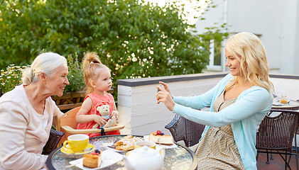 Image showing woman photographing her family at cafe