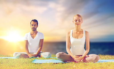 Image showing happy couple making yoga and meditating outdoors