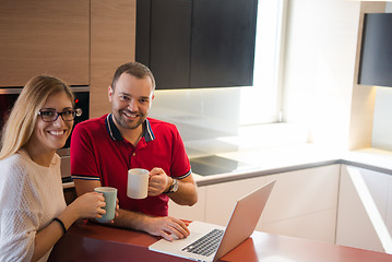 Image showing couple drinking coffee and using laptop at home