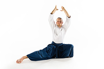 Image showing Aikido master practices defense posture. Healthy lifestyle and sports concept. Man with beard in white kimono on white background.