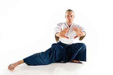 Image showing Aikido master practices defense posture. Healthy lifestyle and sports concept. Man with beard in white kimono on white background.