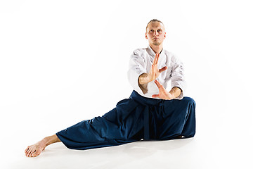 Image showing Aikido master practices defense posture. Healthy lifestyle and sports concept. Man with beard in white kimono on white background.