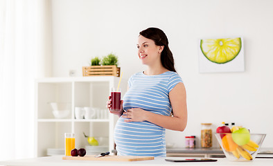 Image showing happy pregnant woman drinking juice at home