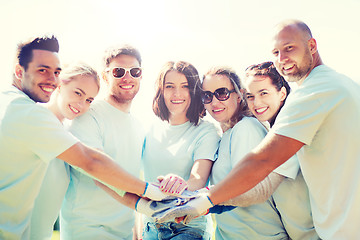 Image showing group of volunteers putting hands on top in park