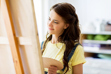 Image showing student girl with easel painting at art school