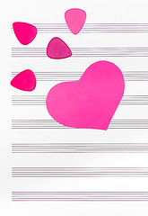 Image showing Pink heart and guitar picks on empty sheet music paper