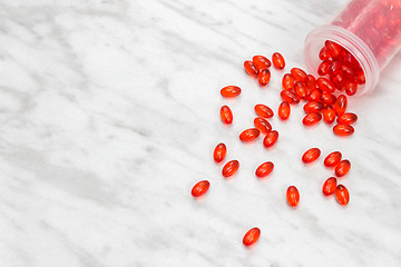 Image showing Bottle with red shiny pills on marble background