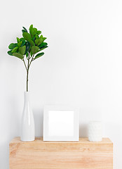 Image showing Stylish decor with white picture frame, ficus leaves and candle