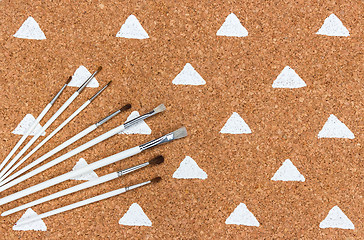 Image showing Paintbrushes on cork background with painted triangles