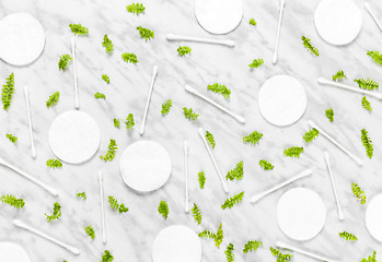 Image showing Cotton pads, swabs and green leaves on marble background