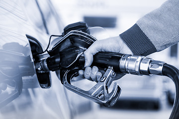 Image showing Closeup of mans hand pumping gasoline fuel in car at gas station.